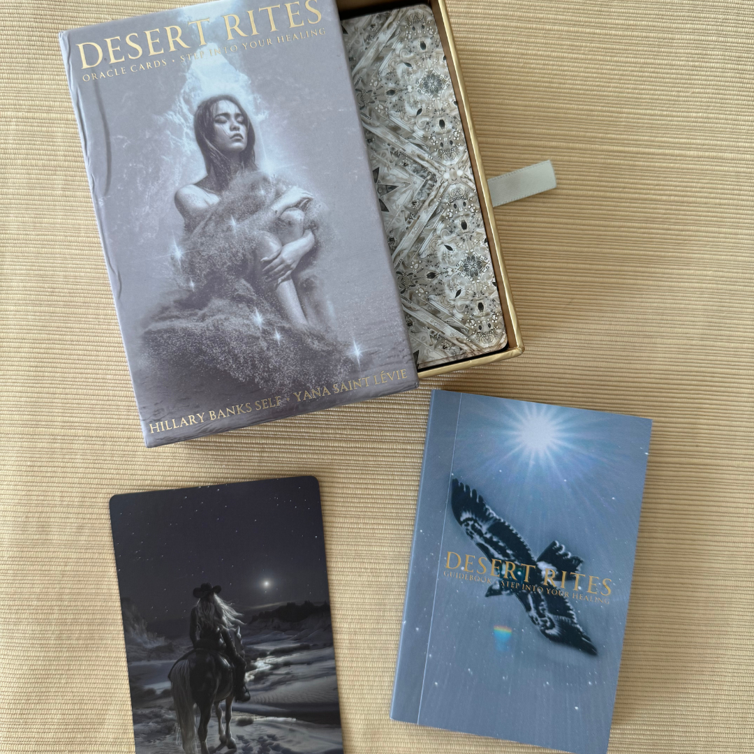 Desert Rites Oracle 44-card deck with gold foil edges and full-color desert healing artwork. Card backs are visible within the box as pictured.  Guidebook is displayed to the bottom right of the photo.  One card face is shown in the bottom left of the image.