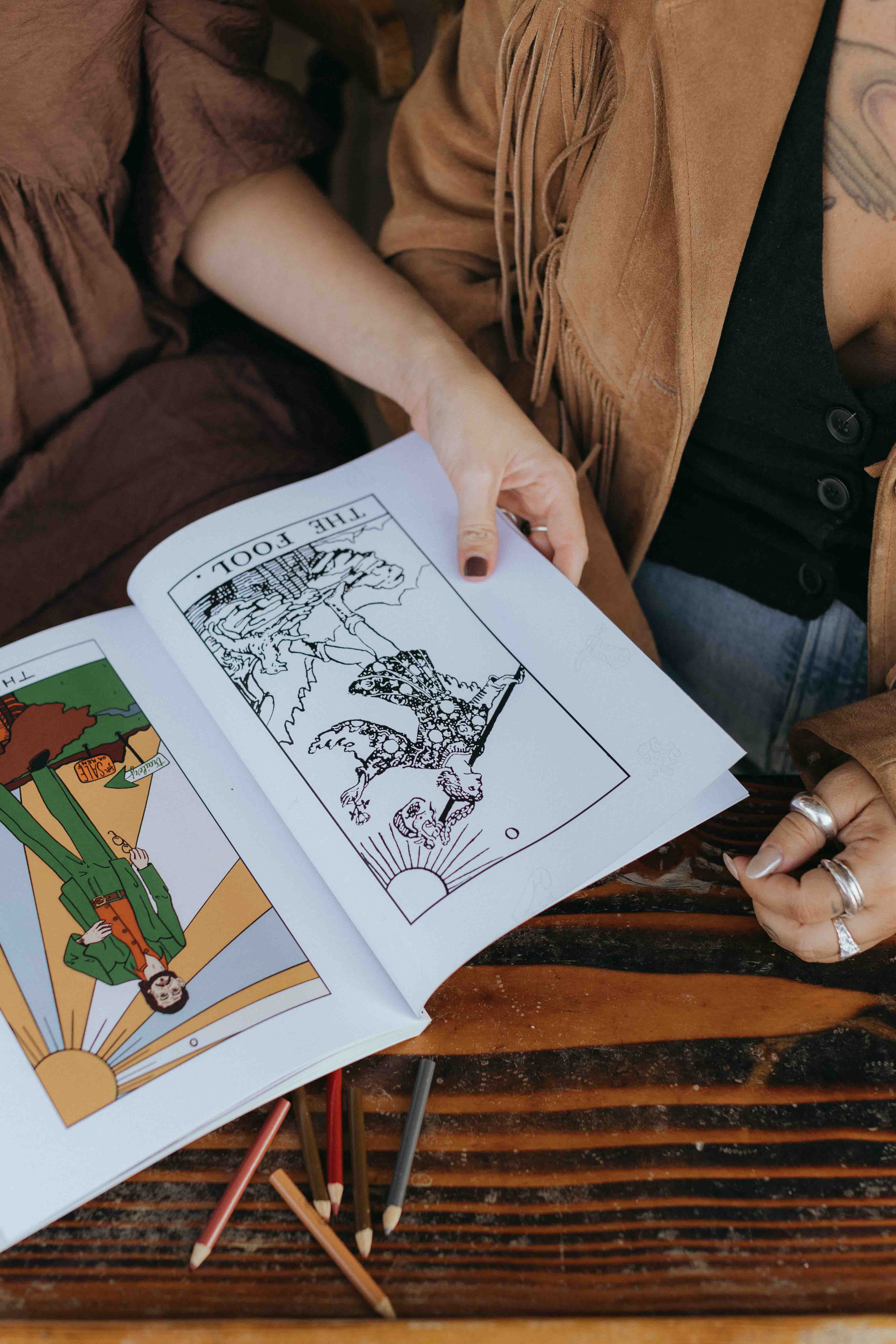 Interior pages of The Honky Tonk Tarot book displaying detailed line drawings of country music legends. Learn the complex language of tarot by making simple country western music associations. In this photo we see RWT traditional tarot version of The Fool Card alongside The Honky Tonk Tarot version of The Fool Card, which features Roger Miller.