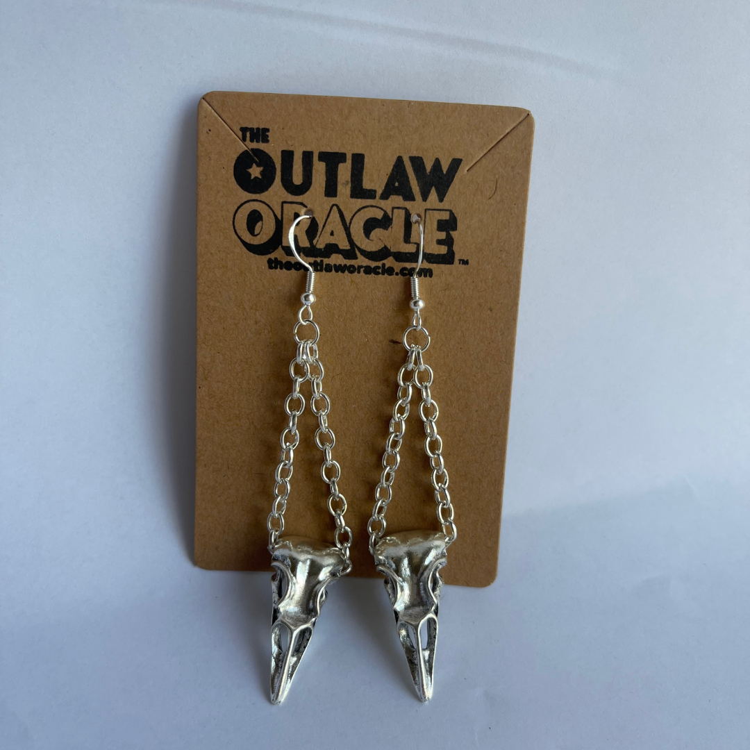 Tibetan silver birdskull earrings with silver chains photographed as sold in The Outlaw Oracle's mystical jewelry collection. 